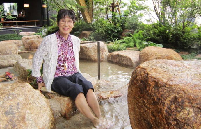 温泉旅行で足湯につかるシニア女性